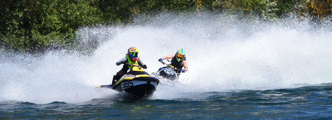 Jet Ski Racers in competitive event on lake making a lot of spray.