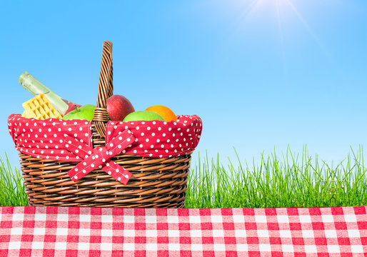a picnic table covered with checkered tablecloth and picnic basket