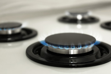 Fototapeta na wymiar Gas burner with blue flame on modern stove, closeup