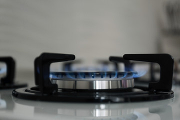 Fototapeta na wymiar Gas burner with blue flame on modern stove, closeup. Space for text