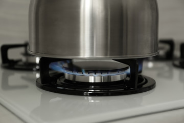 Steel kettle on modern gas stove, closeup