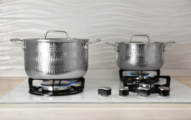 Shiny steel saucepans on modern gas stove