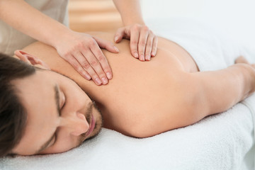 Obraz na płótnie Canvas Handsome man receiving back massage in spa salon