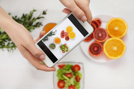 Closeup of food blogger photographing fresh fruits and vegetables with mobile phone, top view