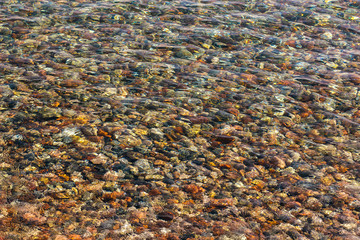 fuzzy colorful stone in shallow water bottom mountain river shoreline from above 