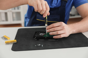 Male technician repairing hard drive at table, closeup