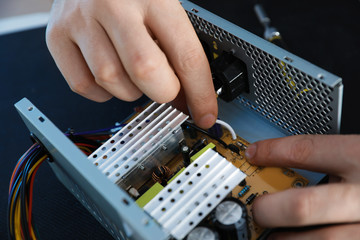Male technician repairing power supply unit at table, closeup