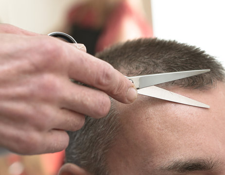 Haircutting process in the hairdresser. man in the salon smoothes his hair. Hands with scissors. Stock photos for design