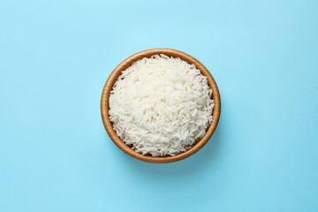 Bowl of tasty cooked rice on color background, top view