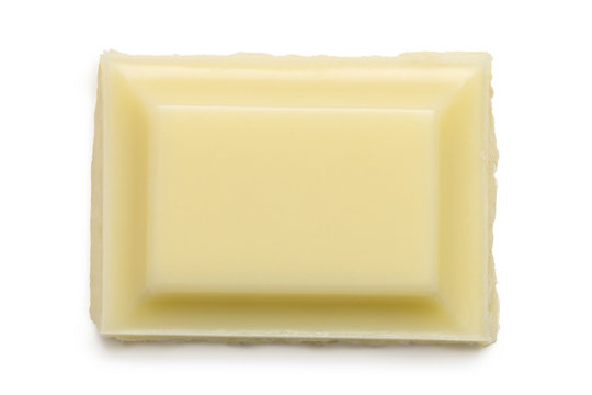 Single square of white chocolate isolated on white from above. Rough edge.