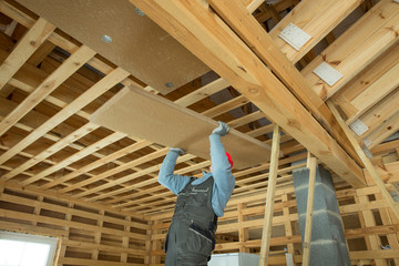 Naklejka na ściany i meble Construction worker thermally insulating eco wooden frame house
