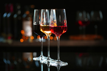 Row of glasses with different wines on bar counter against blurred background