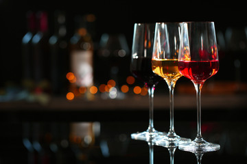 Row of glasses with different wines on bar counter against blurred background. Space for text