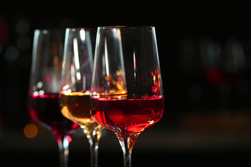 Row of glasses with different wines against blurred background, closeup. Space for text