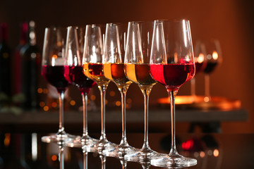 Row of glasses with different wines on bar counter against blurred background