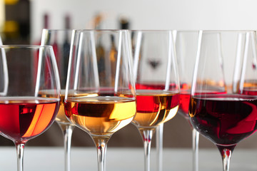 Glasses with different wines on blurred background, closeup