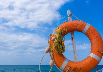 Orange emergency lifebuoy on a pebbly sea beach, close up