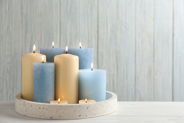 Burning candles in tray on table. Space for text