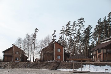 The concept of a country holiday. Wooden houses on the shore of the lake covered with ice and snow.