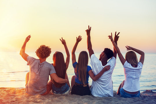 Group Of Happy Friends Having Fun At Ocean Beach At Dawn