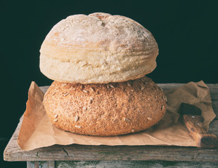 two loaves of baked round bread lay on brown paper