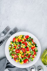 Fresh summer corn salad bowl with tomatoes, cucumbers, red onions and parsley.