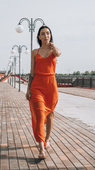 The girl walks along the promenade. The girl walks next to the water.