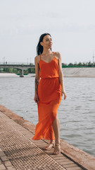 The girl walks along the promenade. The girl walks next to the water.