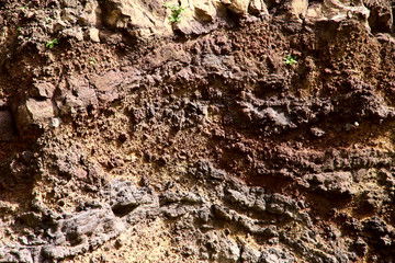 The background texture of the surface of brown soil is of vulcanic origin. View from above, cropped shot, horizontal, close-up, nobody. The concept of construction and nature.