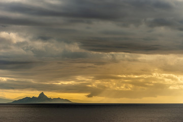 Naklejka na ściany i meble East Nusa Tenggara Island, Indonesia - February 24, 2019: Early morning at sunrise. Southside coast off Sessok in Savu Sea under cloudscape with yellow and darker patches. Dark sea, hill silhouette of