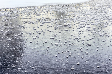 Fototapeta na wymiar Flat ice on frozen pond, with small patches of crystalline snow.