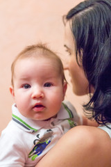 Young beautiful mother brunette holding her arms her little son
