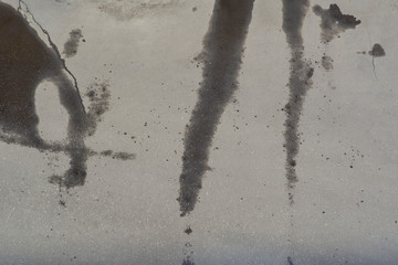The texture of the asphalt road, partially dry, partially covered with wet spots and drips. View from above.