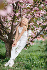 portrait of a beautiful little child girl with sakura flowers on a sunny spring day