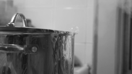 Detail of boiling pot of hot water on the stove. Bubbling over with steam. Black and white.