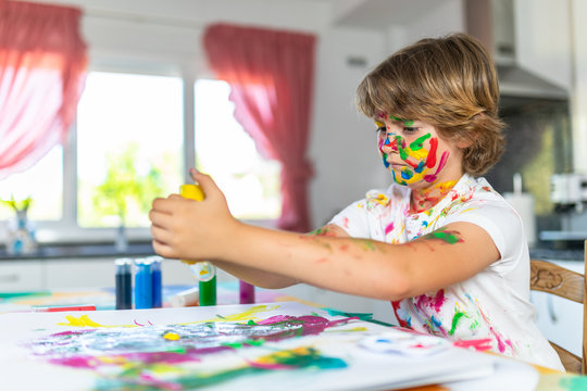 Blond child painting with colored face stained