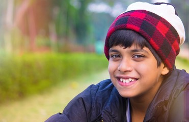 Fototapeta premium Cute boy with a Warm Smiling Face Against a Green blurry background