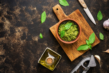 Fototapeta na wymiar Pesto sauce, basil leaves, garlic and olive oil on a dark rustic background. Overhead view,copy space