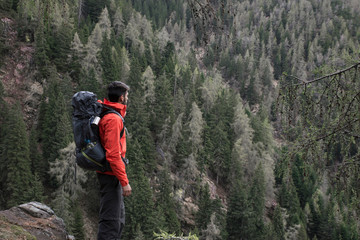 Portrait of an athletic healthy man hiking in nature and looking the at the view. High mountain fir forest background.