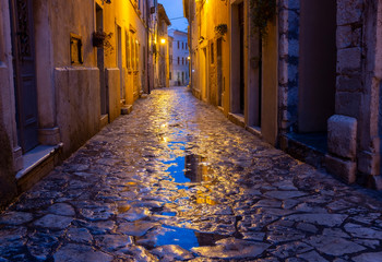 Fototapeta na wymiar Street in Rovinj after rain with feflections in puddles