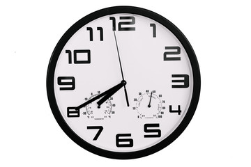 simple classic black and white round wall clock isolated on white. Clock with arabic numerals on wall shows 19:40 , 7:20