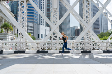 Young asian woman runner running on city bridge road