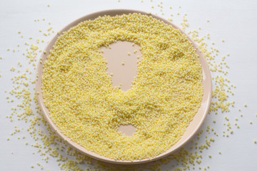 Dry couscous on a plate on a white background. Spilled couscous.