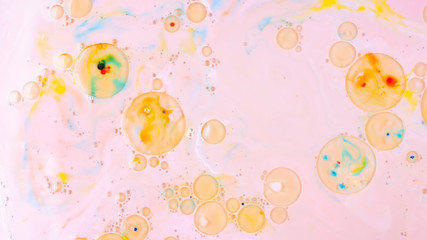 Fluid art. Multicolored background with oil on liquid. Abstract golden pink background on liquid. Pattern with multicolored spots