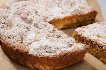 Round sweet cake with icing sugar and flowers.