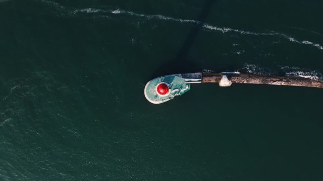 Aerial top view of white lighthouse near sea port