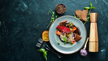 Herring tartar in a plate. Rustic style. Top view. Free space for your text.