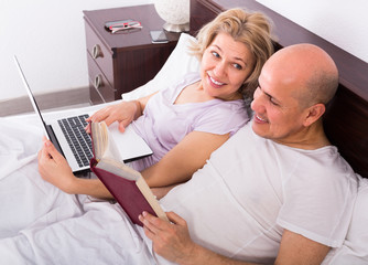 Fototapeta premium Mature couple in bed with laptop .