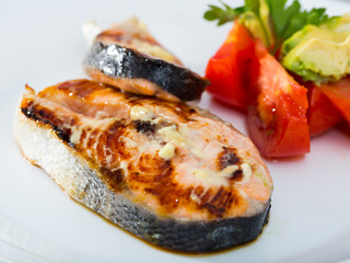 Deliciously steak of  fried salmon with tomatoes and avocado on plate