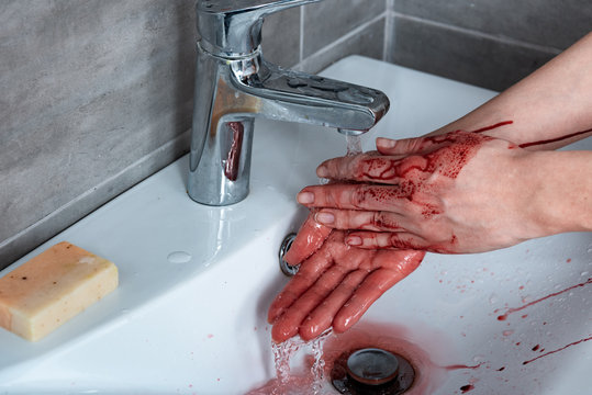 partial view of woman washing bleeding hands in bathroom